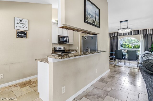 kitchen with kitchen peninsula, appliances with stainless steel finishes, dark stone counters, white cabinetry, and hanging light fixtures