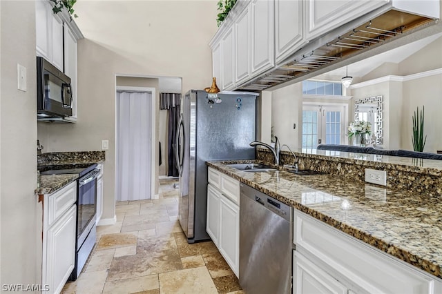 kitchen with appliances with stainless steel finishes, french doors, vaulted ceiling, dark stone countertops, and white cabinetry