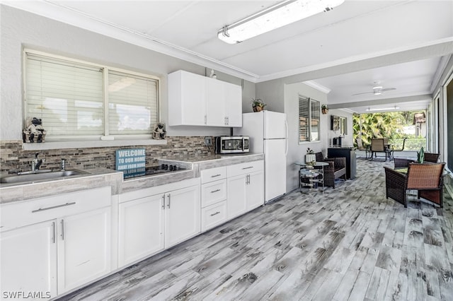 kitchen with tasteful backsplash, ceiling fan, sink, white fridge, and white cabinetry