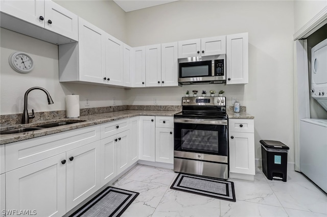 kitchen with white cabinets, stainless steel appliances, stacked washer / dryer, and sink