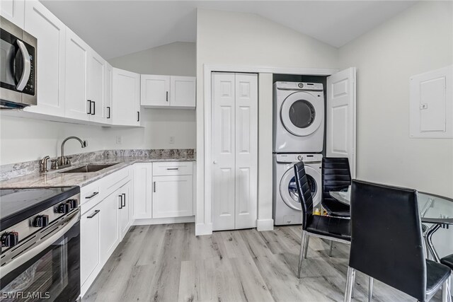 clothes washing area with sink, light wood-type flooring, stacked washer and dryer, and electric panel