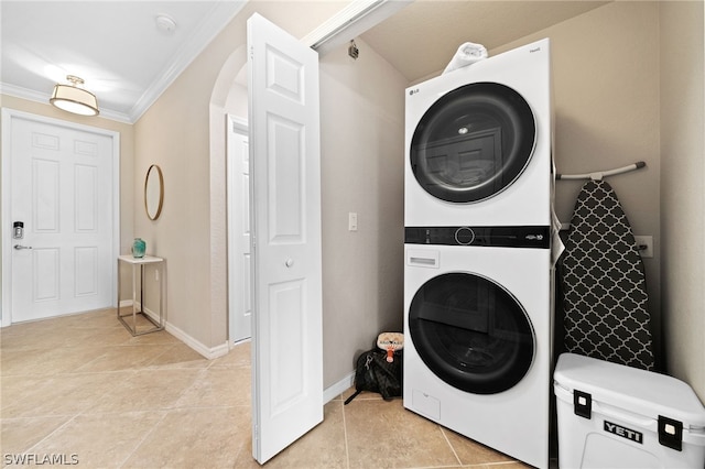 washroom with light tile patterned flooring, crown molding, and stacked washing maching and dryer