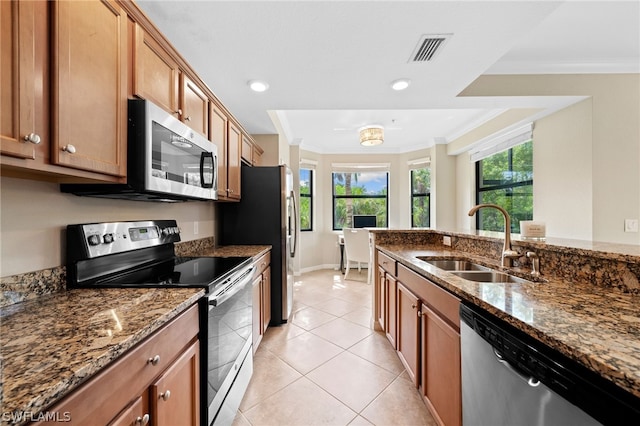 kitchen with stone counters, appliances with stainless steel finishes, light tile patterned flooring, and sink