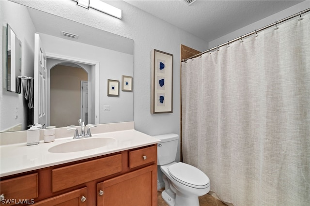 bathroom featuring vanity, toilet, tile patterned floors, and a textured ceiling