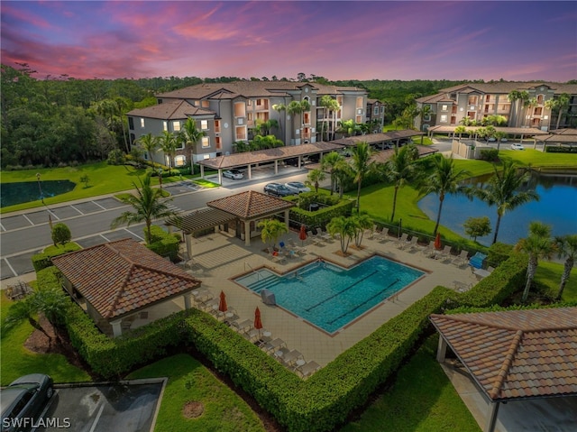 pool at dusk with a yard and a water view