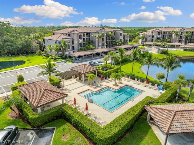 view of pool featuring a water view, a patio, and a lawn