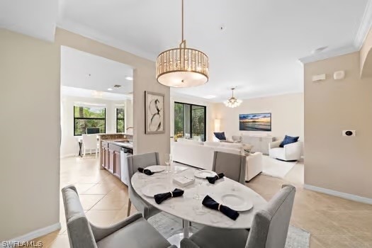 dining area featuring ornamental molding, sink, an inviting chandelier, and light tile patterned floors