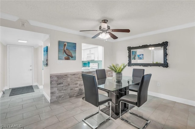 tiled dining area featuring ceiling fan, crown molding, baseboards, and a textured ceiling