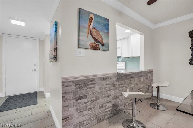 interior space featuring light tile patterned floors, baseboards, and ornamental molding