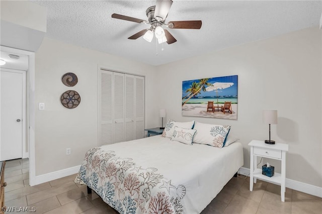 tiled bedroom with a closet, a textured ceiling, baseboards, and a ceiling fan