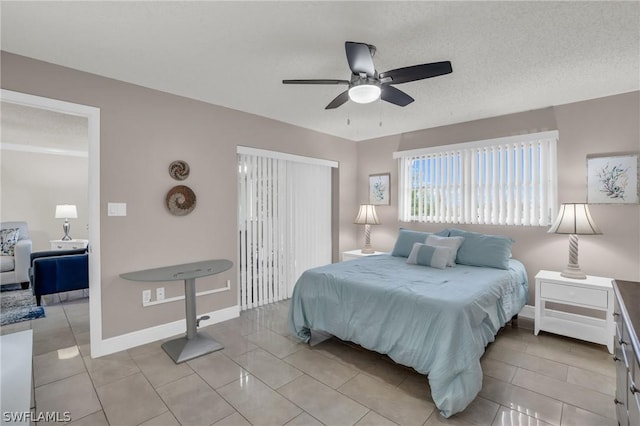 bedroom with light tile patterned floors, a textured ceiling, and baseboards