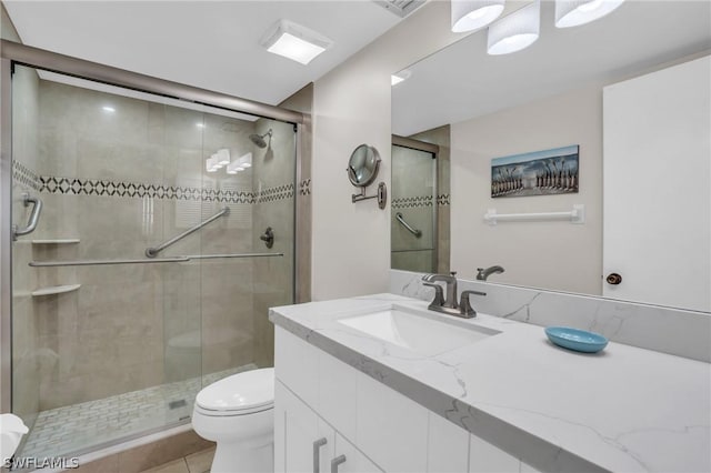 bathroom with vanity, tile patterned floors, toilet, and a stall shower