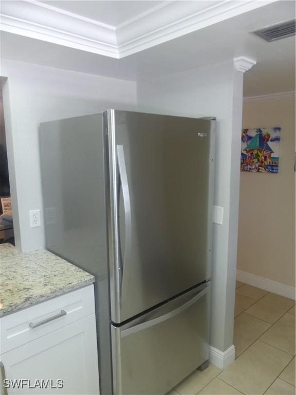 details featuring visible vents, ornamental molding, freestanding refrigerator, white cabinets, and light stone countertops