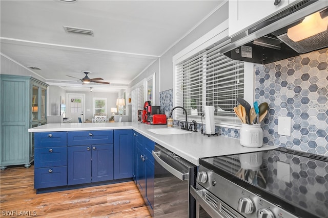 kitchen featuring appliances with stainless steel finishes, decorative backsplash, kitchen peninsula, and light wood-type flooring