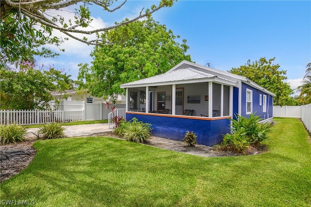 back of property featuring a sunroom and a lawn