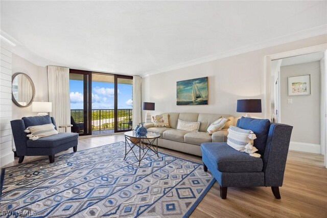 living room with hardwood / wood-style flooring, ornamental molding, and a wall of windows