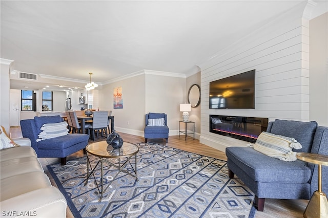 living room with crown molding, a chandelier, and wood-type flooring