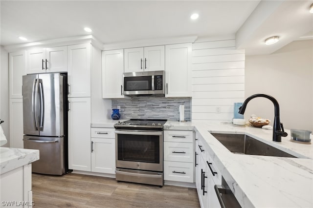 kitchen featuring light stone countertops, stainless steel appliances, wood-type flooring, sink, and white cabinetry