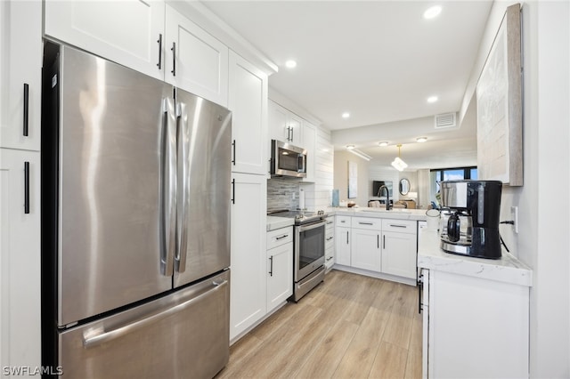 kitchen with light stone countertops, light hardwood / wood-style flooring, tasteful backsplash, white cabinetry, and appliances with stainless steel finishes