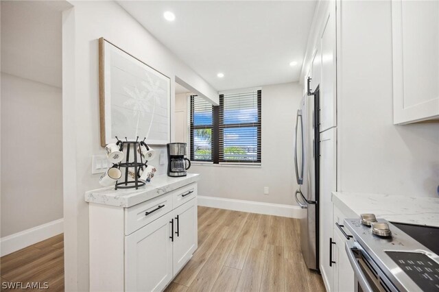 kitchen featuring light hardwood / wood-style flooring, stainless steel fridge, and white cabinetry