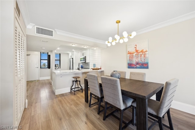 dining area featuring light hardwood / wood-style floors, ornamental molding, and a chandelier