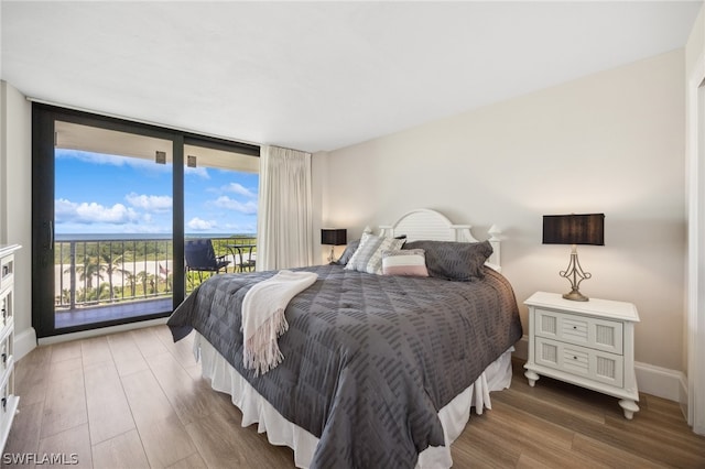 bedroom featuring access to outside, floor to ceiling windows, and wood-type flooring