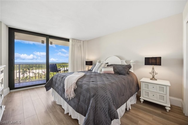 bedroom featuring hardwood / wood-style flooring, access to outside, and floor to ceiling windows