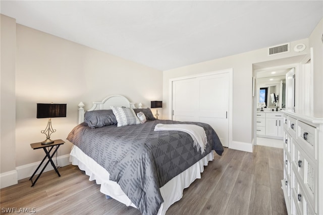 bedroom featuring light hardwood / wood-style floors, a closet, and ensuite bath