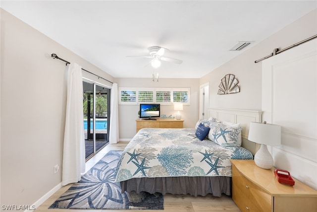 bedroom with access to outside, a barn door, ceiling fan, and light hardwood / wood-style flooring