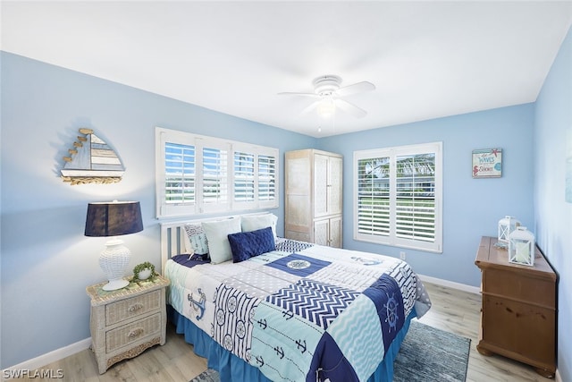 bedroom featuring ceiling fan, light hardwood / wood-style floors, and multiple windows