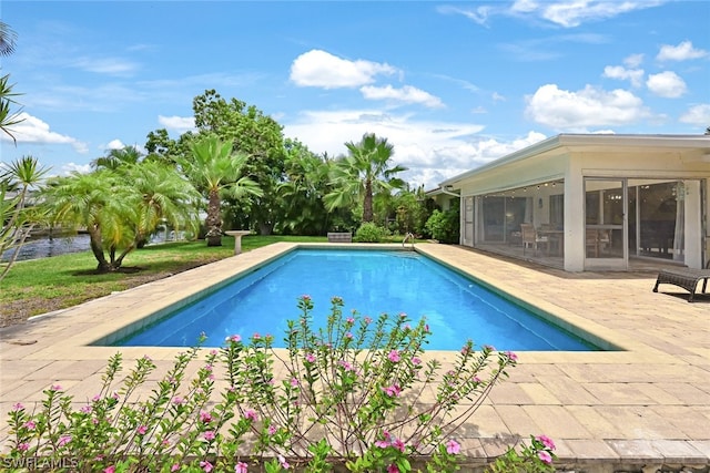 view of swimming pool featuring a sunroom and a patio