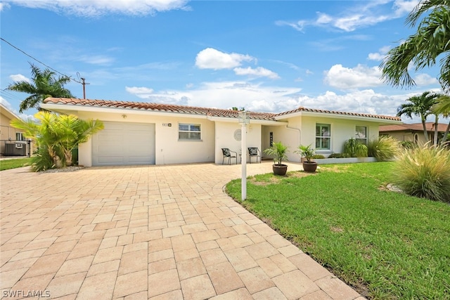 mediterranean / spanish home featuring central AC unit, a garage, and a front yard