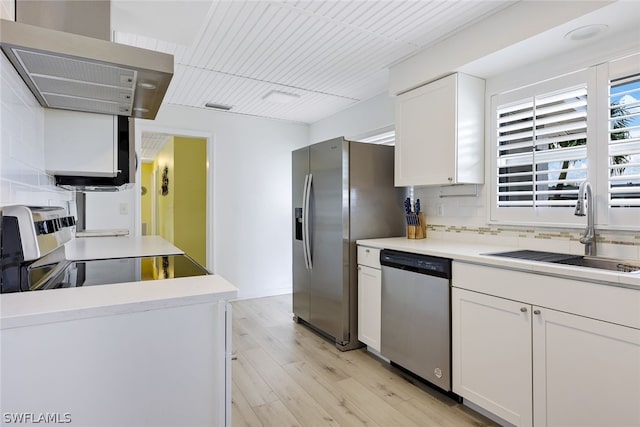 kitchen featuring stainless steel appliances, wall chimney exhaust hood, white cabinetry, and sink