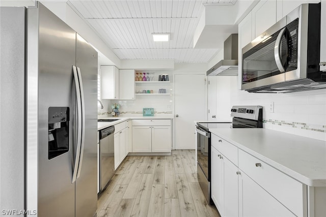 kitchen with stainless steel appliances, wall chimney exhaust hood, white cabinets, and sink