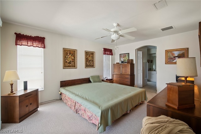 bedroom with light carpet, ceiling fan, and ensuite bath