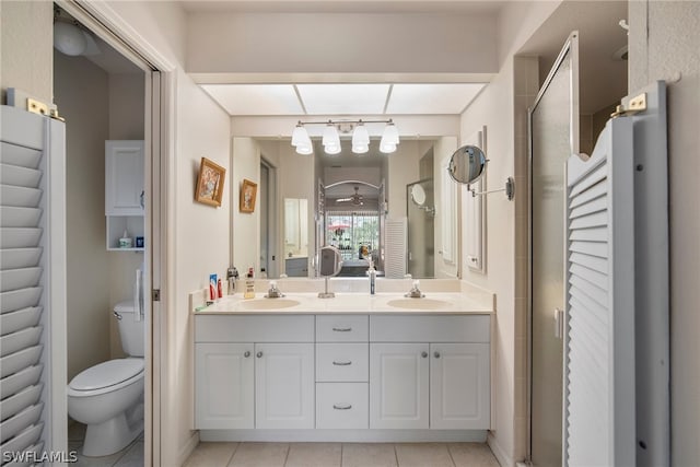 bathroom featuring a shower with shower door, vanity, toilet, and tile patterned floors