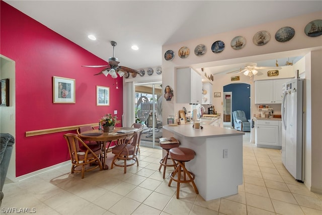 kitchen featuring white cabinets, ceiling fan, a breakfast bar, white fridge, and sink