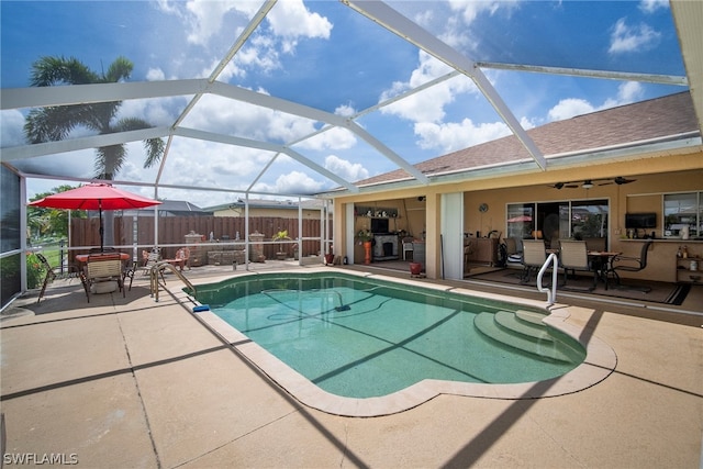 view of swimming pool with a patio, glass enclosure, and ceiling fan