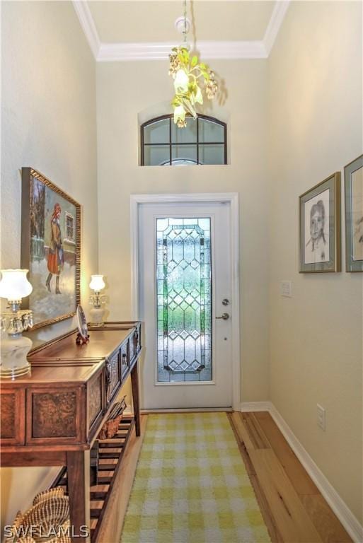 foyer with a towering ceiling, light wood-type flooring, and crown molding