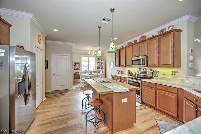 kitchen featuring a center island, stainless steel appliances, crown molding, pendant lighting, and light wood-type flooring