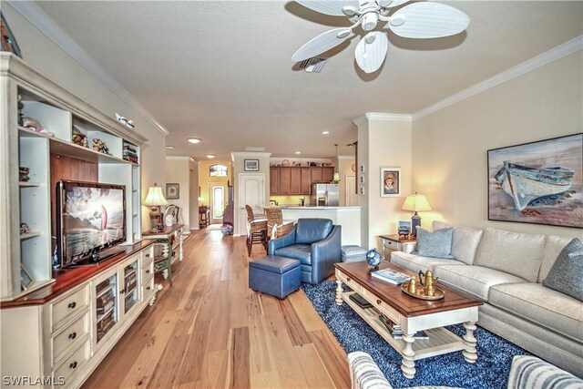 living room featuring ceiling fan, light hardwood / wood-style floors, and ornamental molding