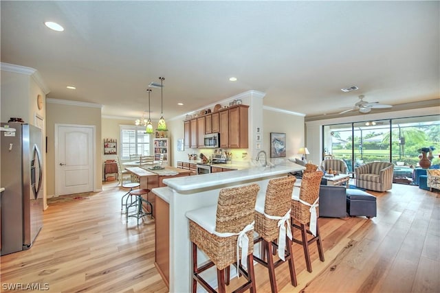 kitchen featuring light hardwood / wood-style floors, a kitchen bar, kitchen peninsula, and stainless steel appliances