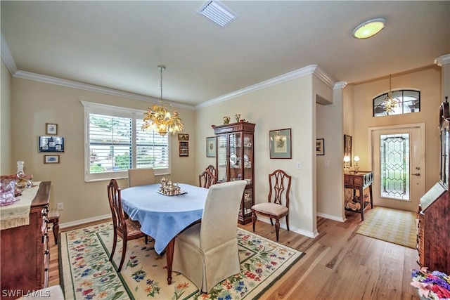 dining space featuring a notable chandelier, ornamental molding, and light hardwood / wood-style flooring