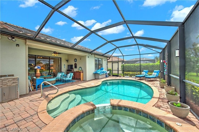 view of swimming pool with glass enclosure, an in ground hot tub, ceiling fan, and a patio