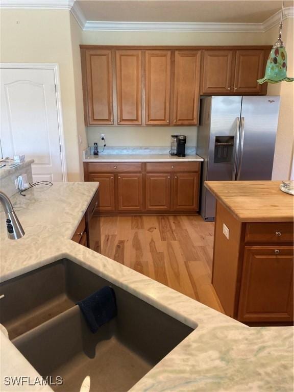 kitchen featuring pendant lighting, light hardwood / wood-style flooring, appliances with stainless steel finishes, and ornamental molding