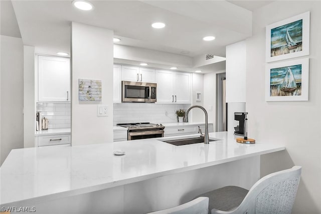 kitchen featuring stainless steel appliances, white cabinetry, sink, and kitchen peninsula