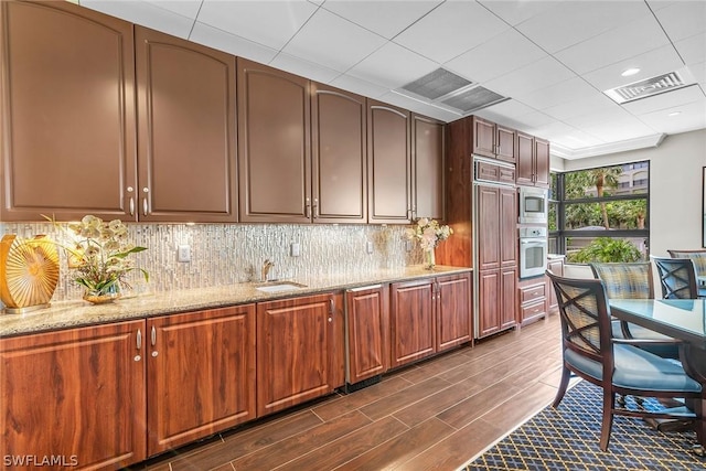 kitchen with tasteful backsplash, sink, light stone countertops, and appliances with stainless steel finishes