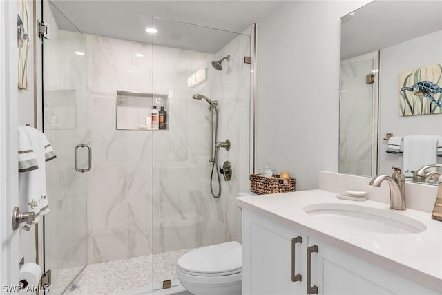 bathroom with an enclosed shower, vanity, and toilet