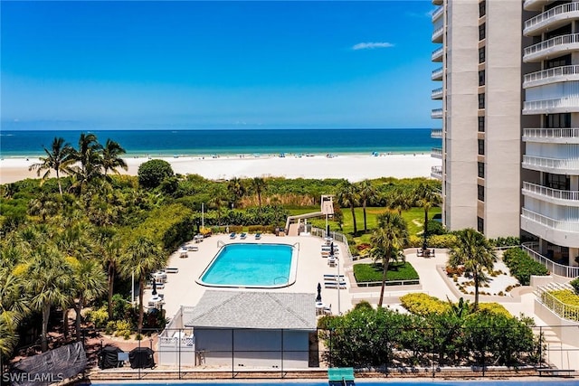 view of swimming pool featuring a water view, a beach view, and a patio