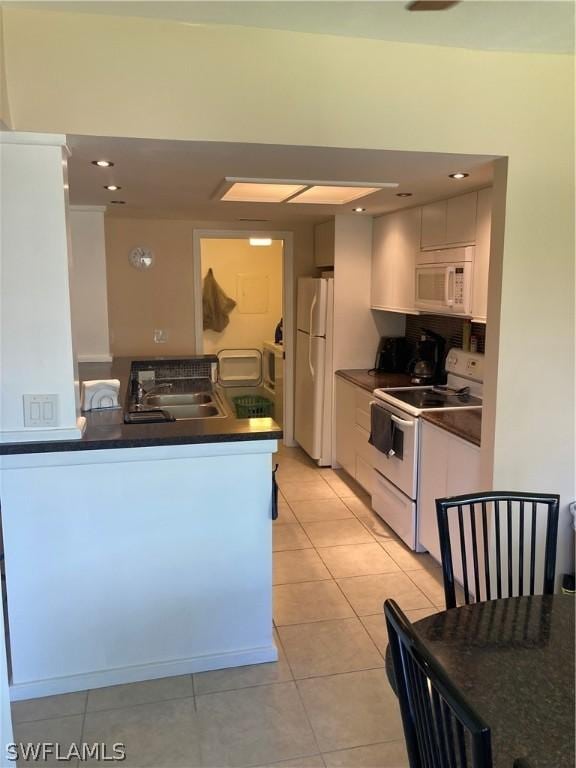64 4th St Unit B201, Bonita Springs, FL 34134 - kitchen featuring white appliances, a sink, dark countertops, white cabinets, and light tile patterned floors